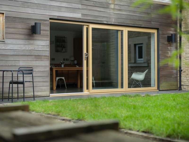 light brown woodgrain foiled uPVC sliding doors opened next to a garden