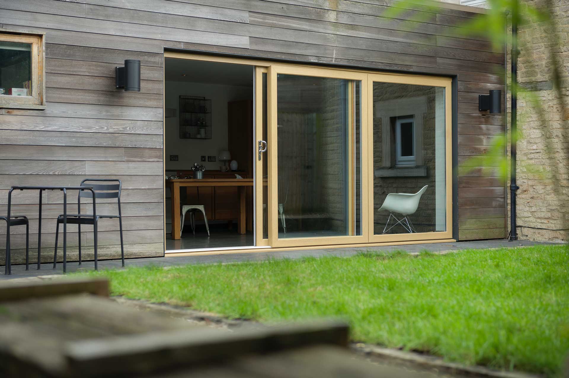 light brown woodgrain foiled uPVC sliding doors opened next to a garden