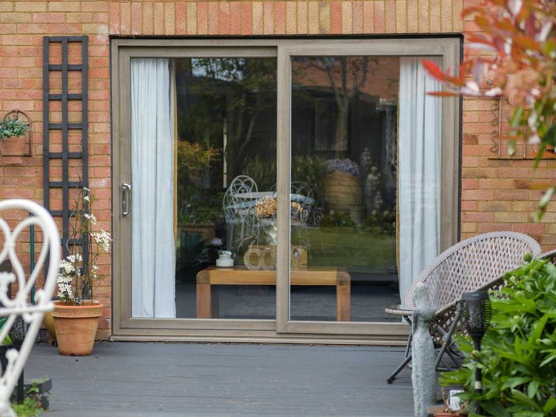 brown woodgrain foil uPVC Patio Sliding Doors from outside in a furnished garden patio