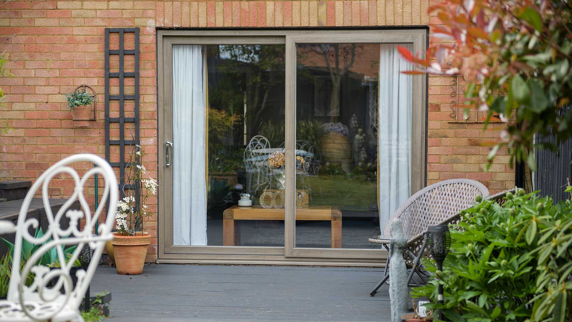 brown woodgrain foil uPVC Patio Sliding Doors from outside in a furnished garden patio